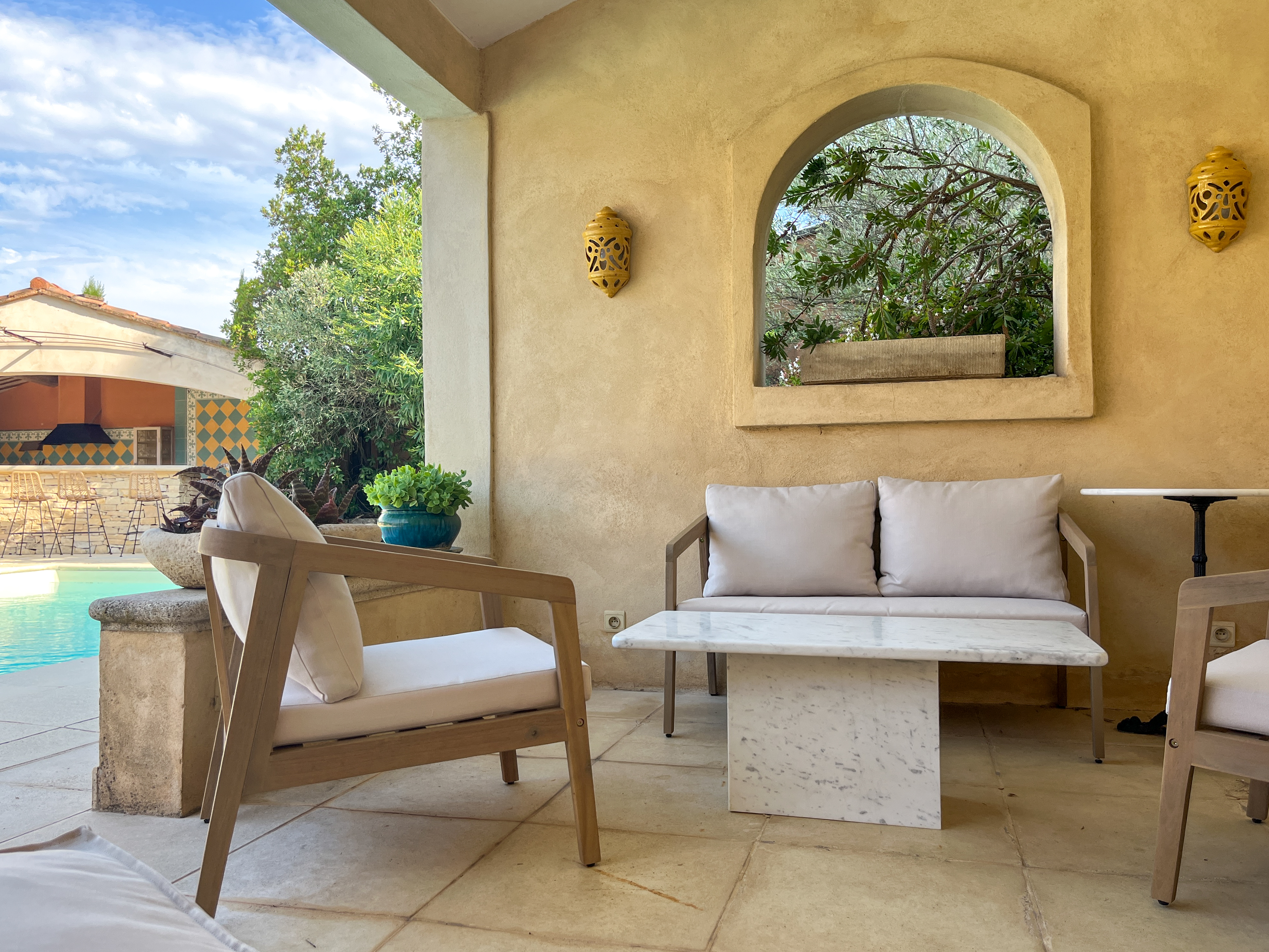 Salon de jardin ombragé offrant une vue apaisante sur la piscine.